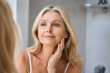 Woman applying moisturizer as part of a menopause skincare routine.